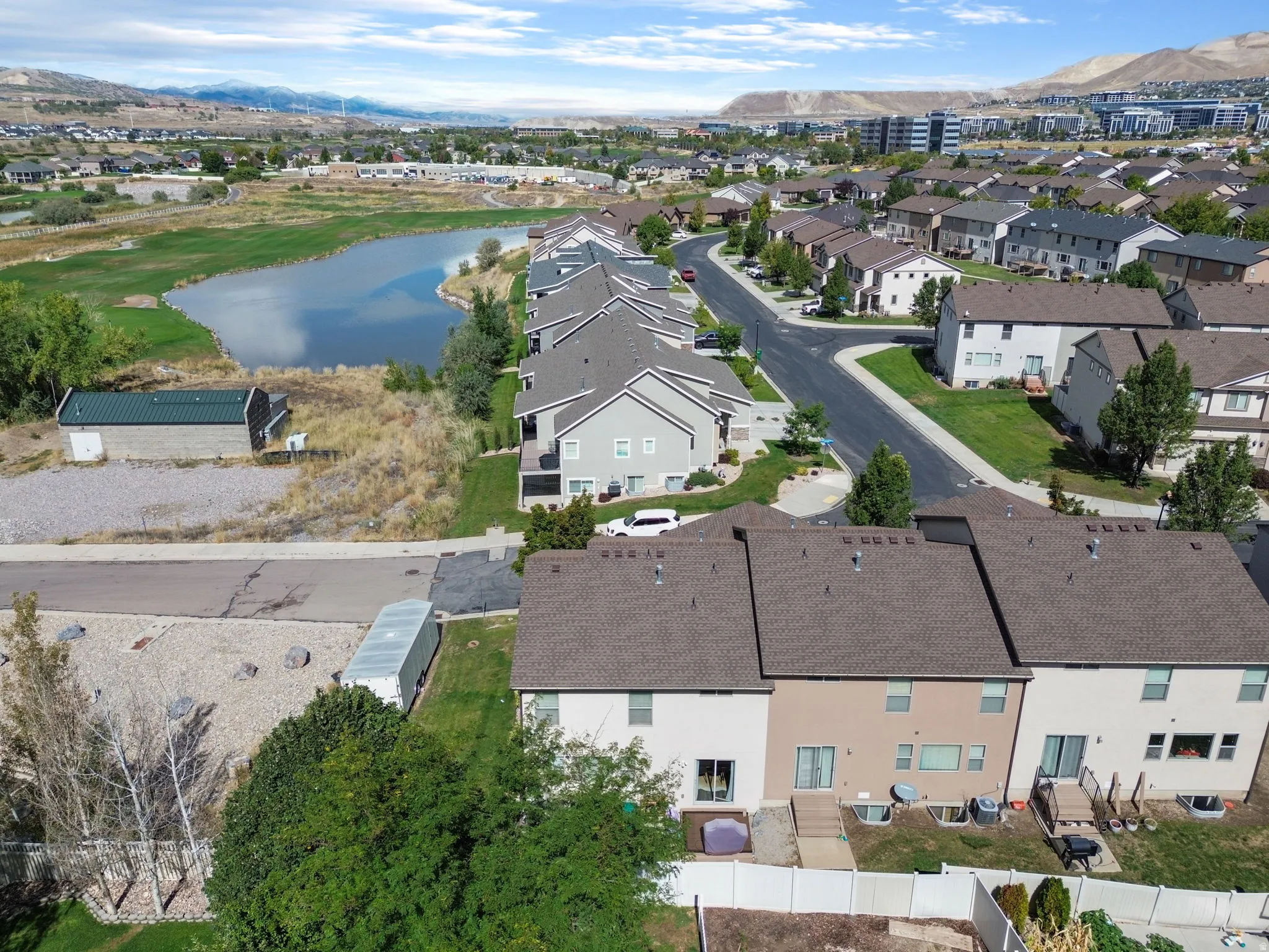 Residential community with a large pond, extensive green spaces, and mountain backdrop