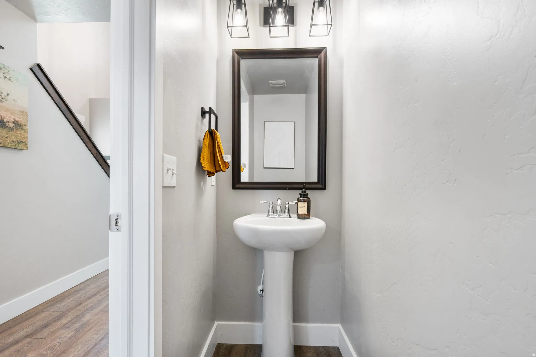 Pedestal sink with chrome faucet, framed mirror, and contemporary vanity lighting