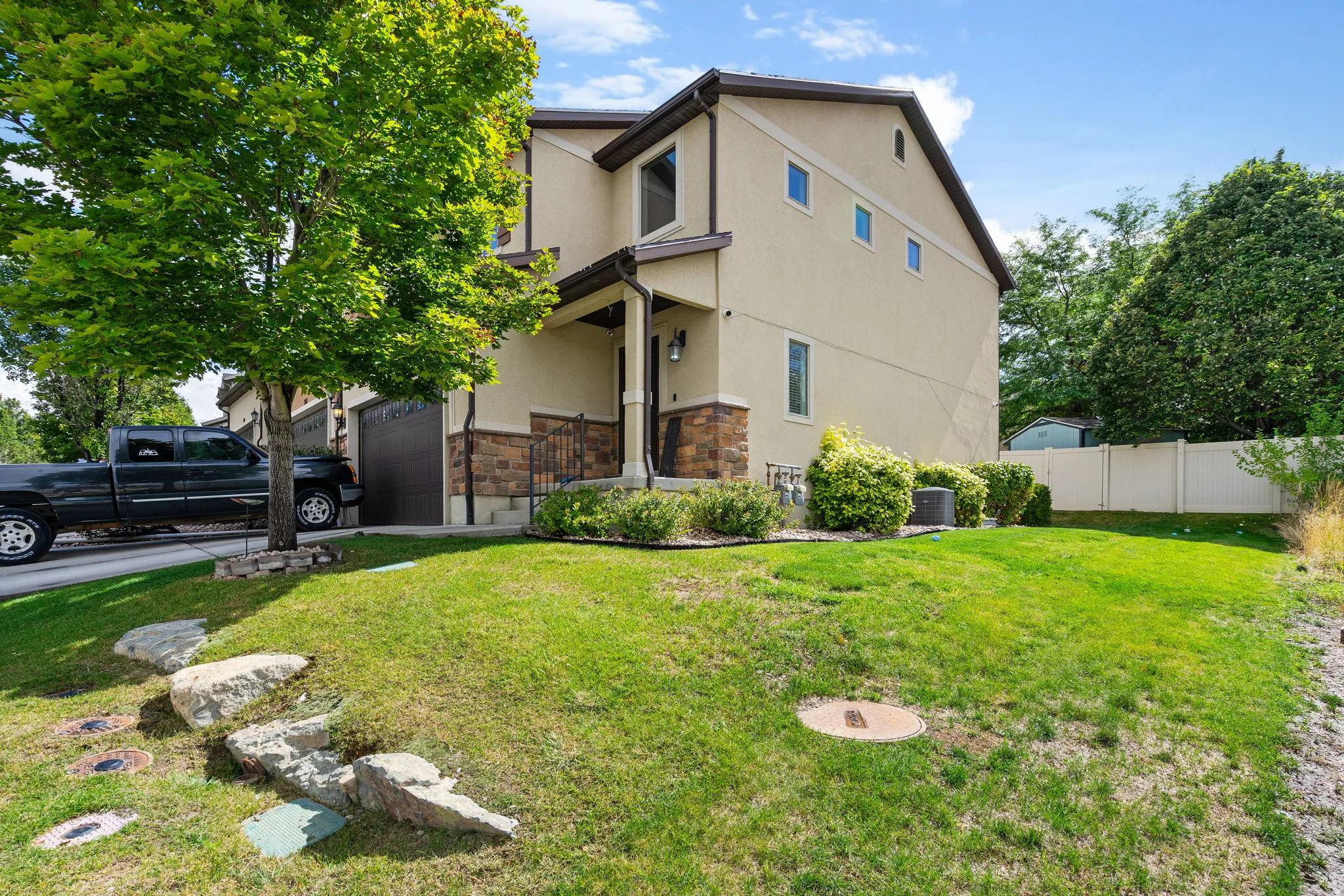 Stucco exterior with stone accents, covered entry, attached garage, and a fenced backyard