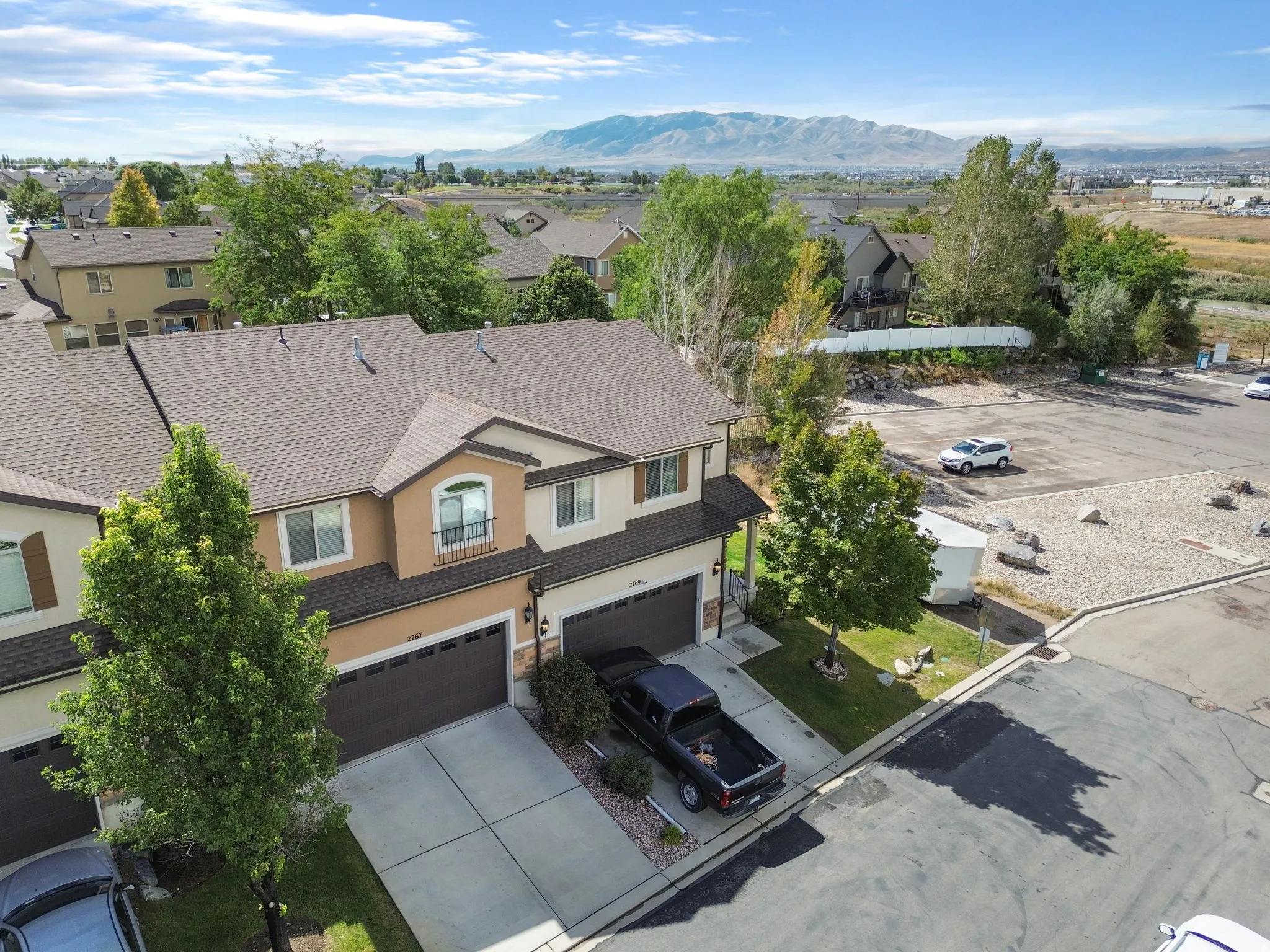 Two-story townhome with an attached two-car garage, stucco exterior, and a prominent balcony