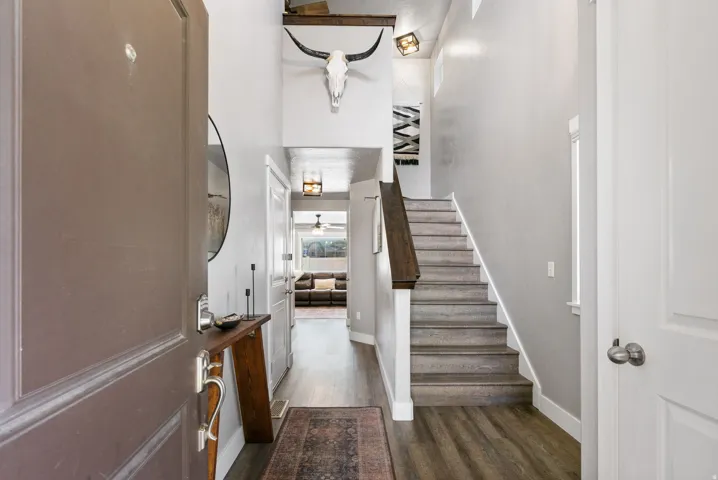 Inviting entryway featuring wood-finish flooring, a contemporary staircase with a dark wood handrail, and high ceilings