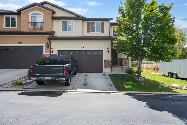Two-story exterior with a two-tone stucco facade, dark brown garage doors, and a covered entry
