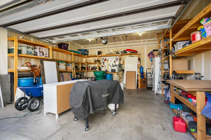 Expansive garage with concrete flooring, overhead garage door, and extensive built-in wooden shelving for storage