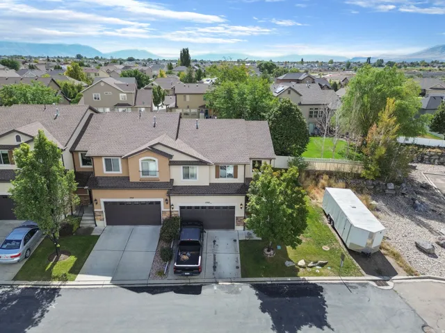 Two-story townhome with a two-car garage, concrete driveway, and a front yard with mature trees