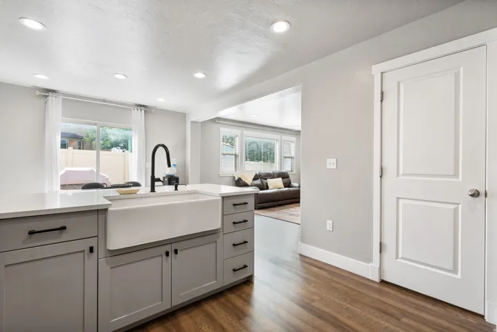 Kitchen island with a white farmhouse sink, matte black gooseneck faucet, light gray cabinetry, and white countertops