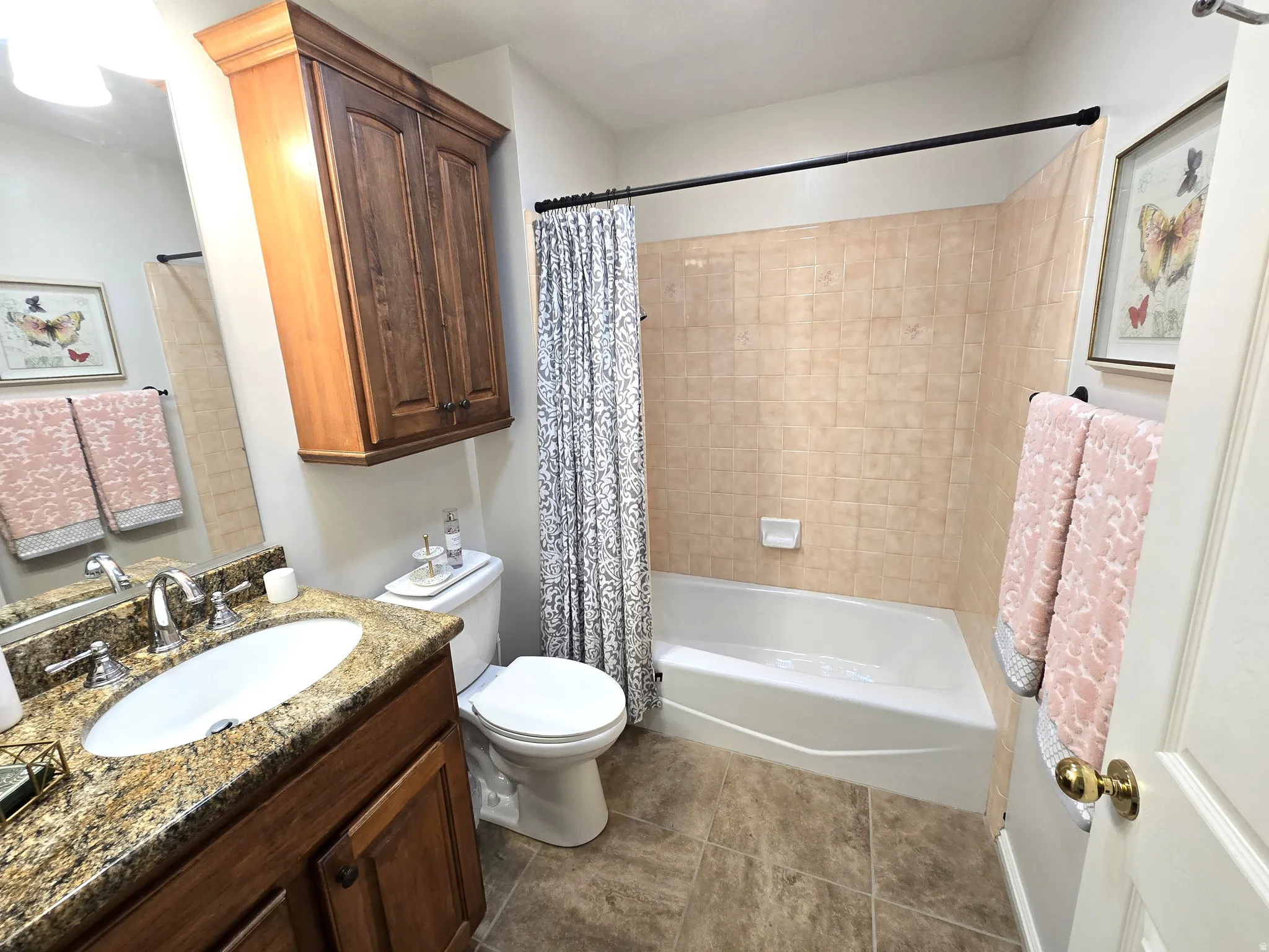 Bathroom featuring a vanity with a granite countertop, undermount sink, built-in wood cabinetry, and a shower/tub combination with tiled surround