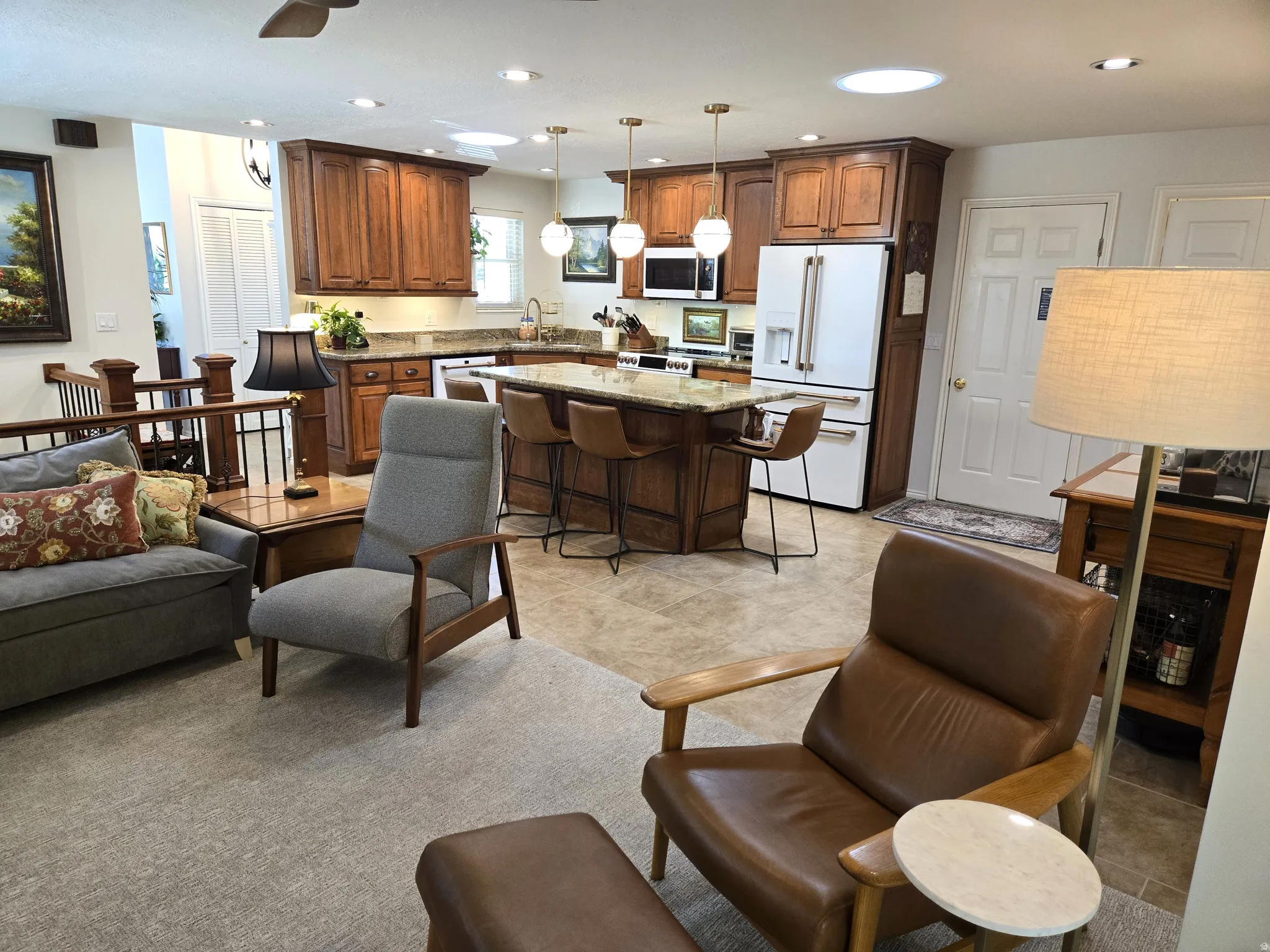Open-concept living space featuring wood cabinetry, stainless steel appliances, a kitchen island with seating, recessed lighting, and a skylight