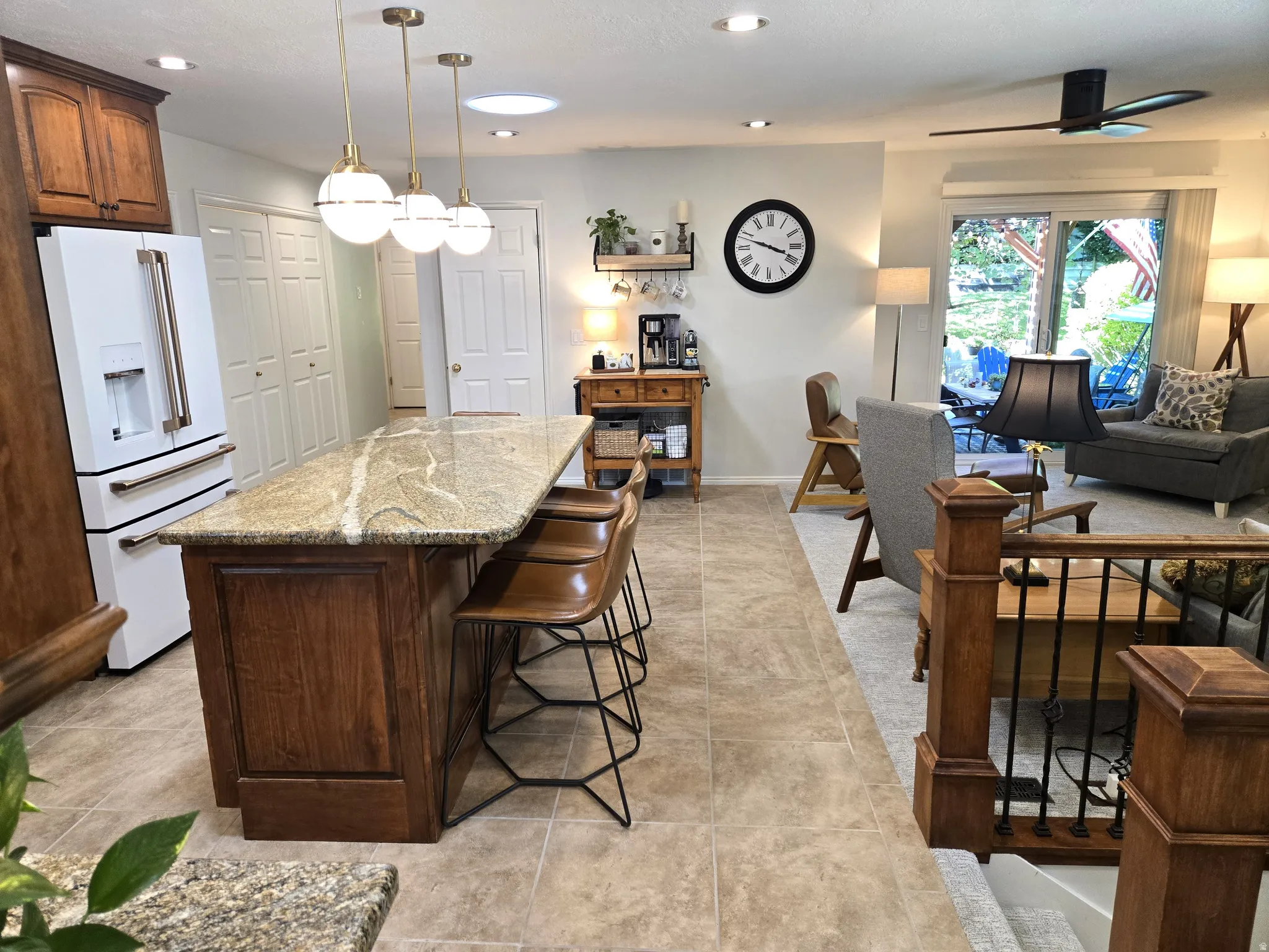 Spacious kitchen island with stone countertop, tile flooring, built-in cabinetry, and recessed lighting