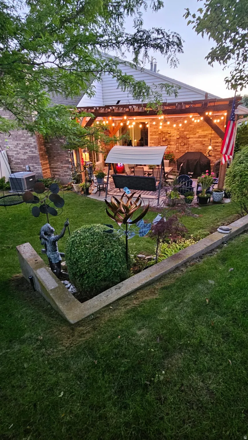 Outdoor living area with a wood pergola, brick exterior, and raised garden beds