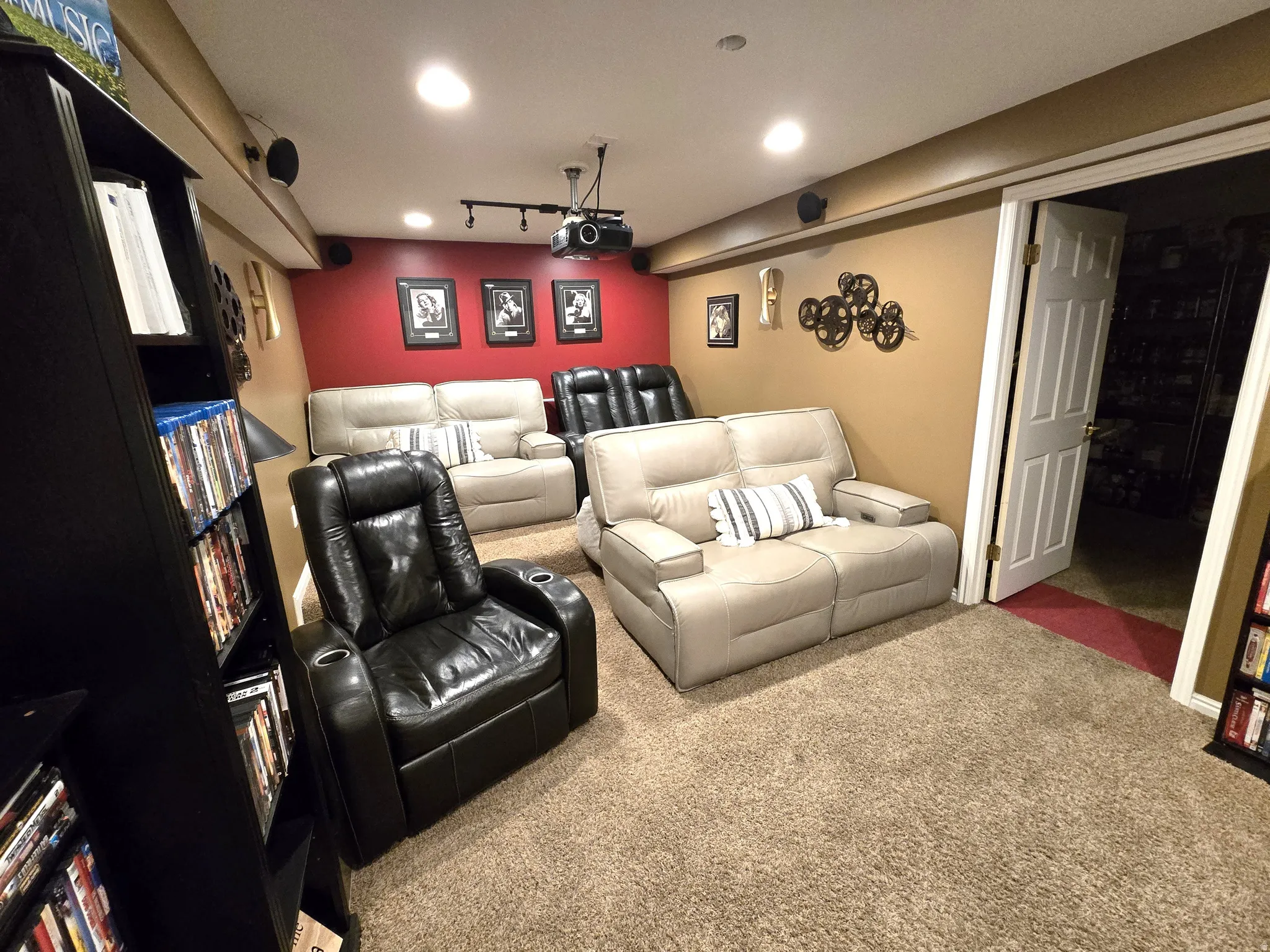 Recessed lighting, wall-mounted speakers, projector on a track light system, and neutral-toned carpeting