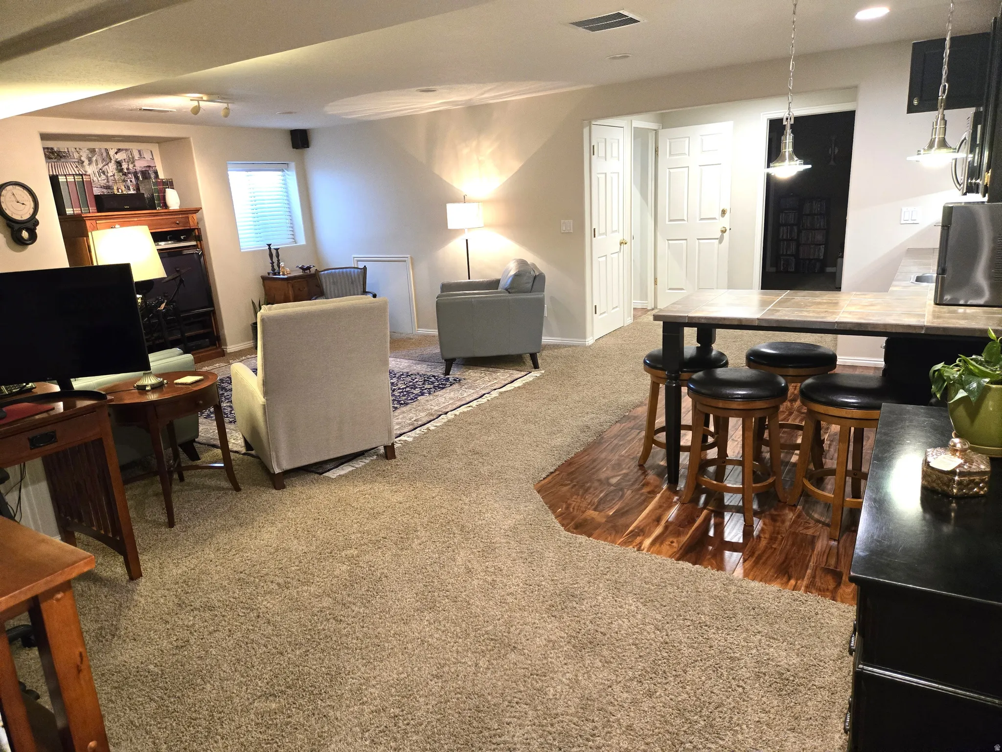 Carpeted flooring throughout, recessed lighting, and a distinct wood-finish flooring area