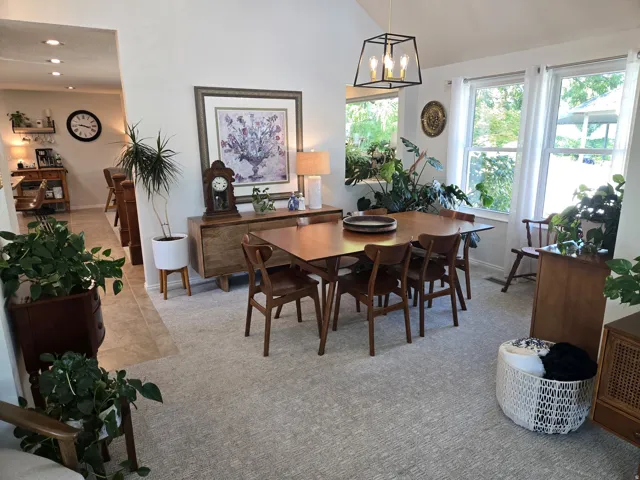 Vaulted ceiling with an open-cage chandelier, multiple windows, built-in shelving, recessed lighting, and tile flooring