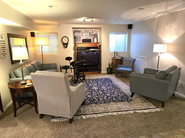 Recessed lighting, wood-finish media console, carpet flooring, and windows with horizontal blinds