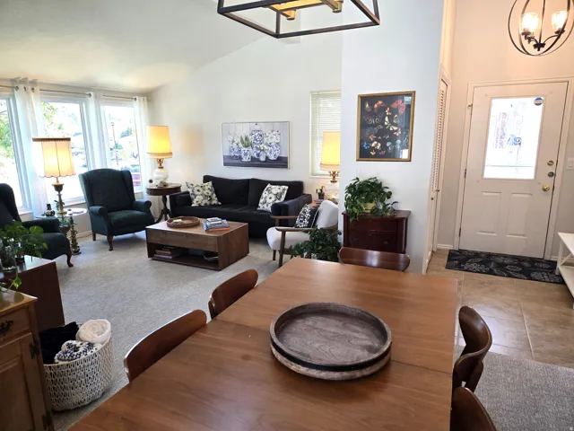 Vaulted ceilings, large windows, wood-finish dining surface, and recessed entry with tile flooring