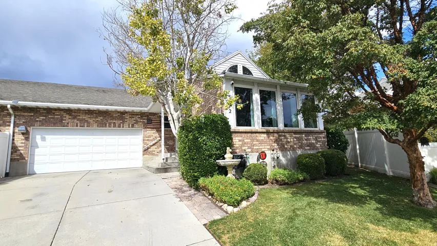 Brick exterior with a peaked roofline, front-facing bay windows, a two-car garage, and established landscaping