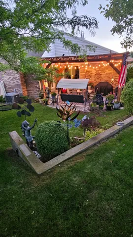 Outdoor living area with a wood pergola, brick exterior, and raised garden beds