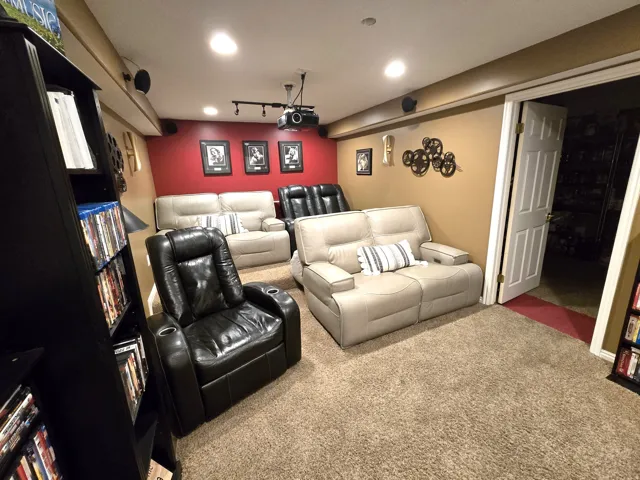 Recessed lighting, wall-mounted speakers, projector on a track light system, and neutral-toned carpeting