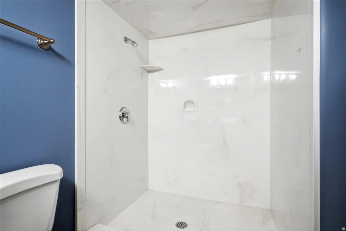 White shower enclosure with integrated shelving and chrome fixtures