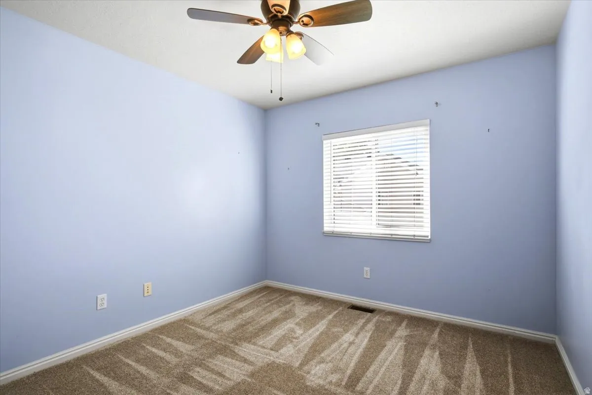 Carpeted room featuring a window with blinds and a ceiling fan