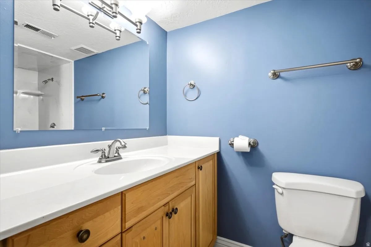 Solid surface vanity with integrated sink, wood cabinetry, chrome faucet, and wall-mounted mirror