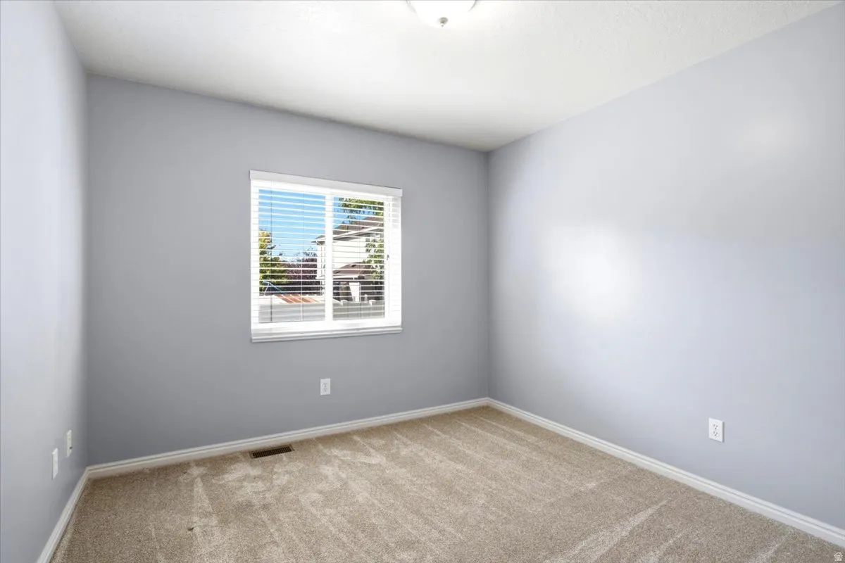 Light grey walls, neutral carpet, white trim, and a window with blinds