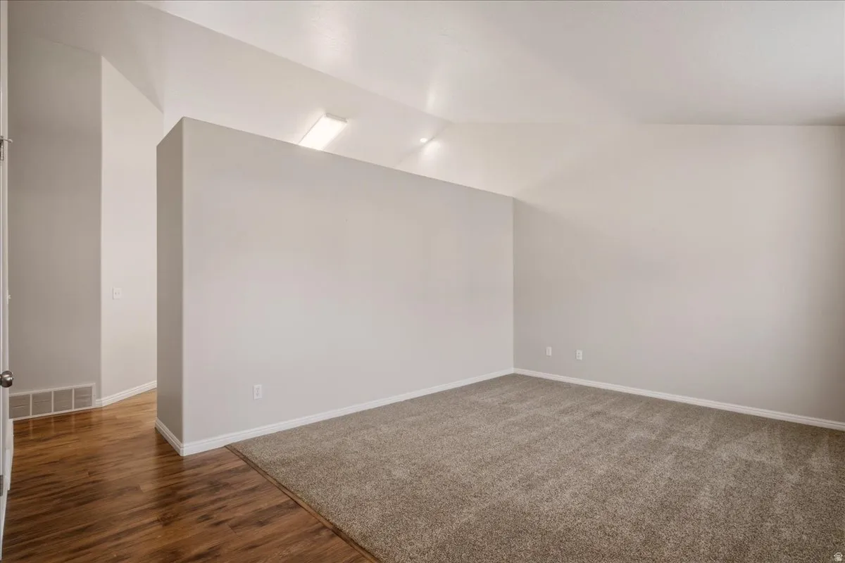 Vaulted ceilings with recessed lighting, wood-finish flooring, and neutral wall tones