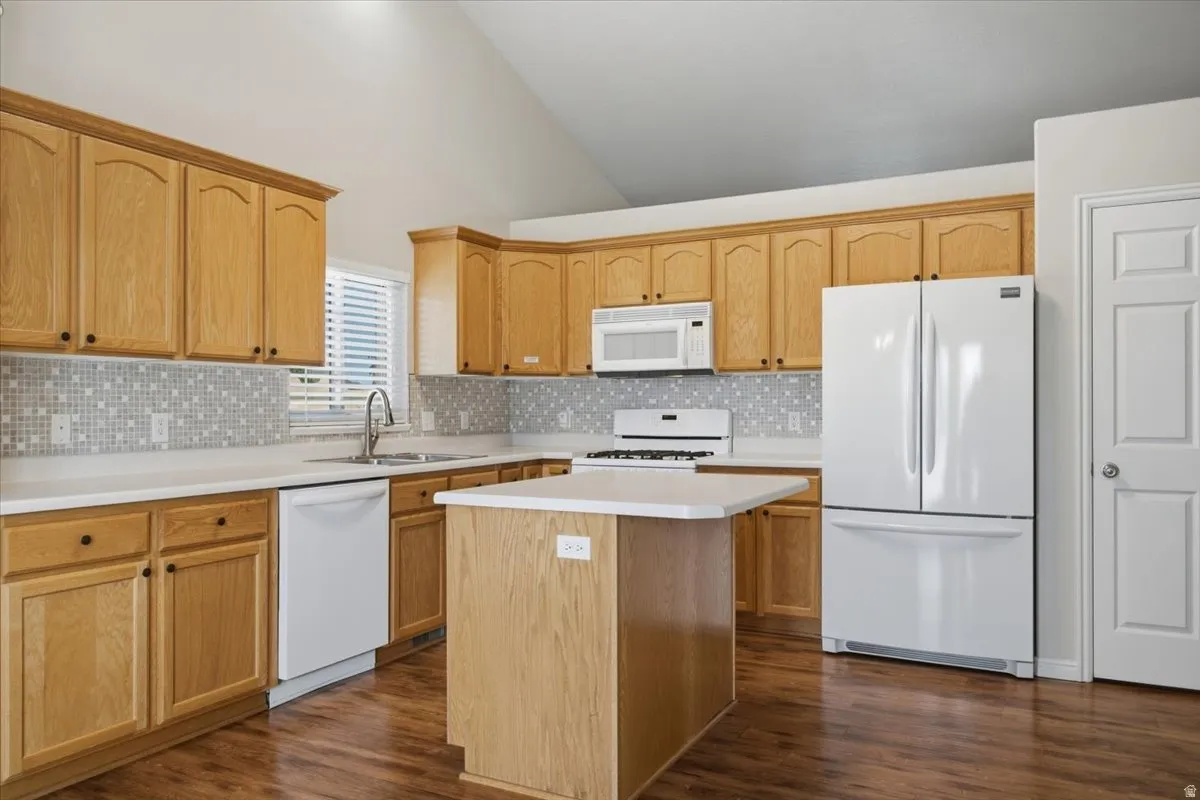 Kitchen featuring wood-finish cabinetry, light countertops, mosaic tile backsplash, a kitchen island, and wood-finish flooring