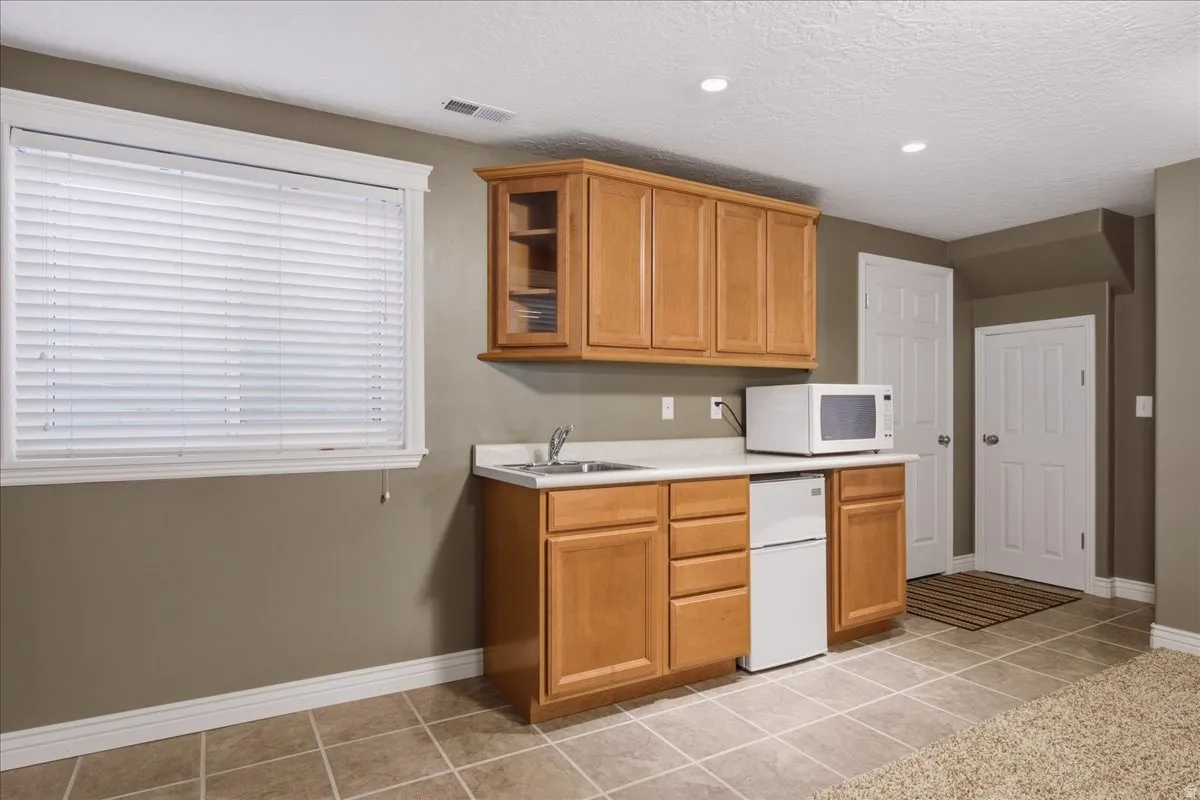 Kitchenette featuring wood cabinetry, laminate countertops, an integrated sink, and recessed lighting