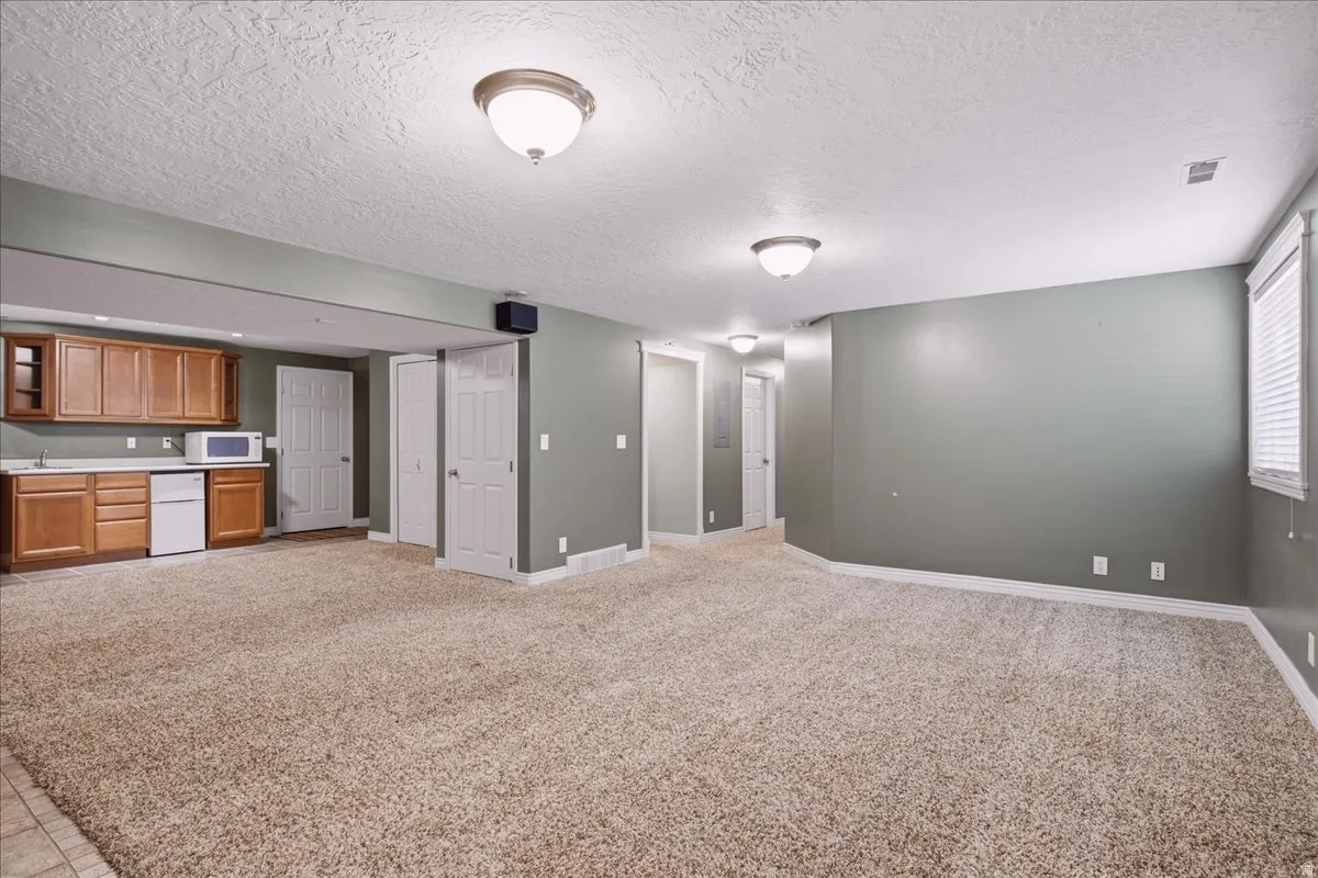 Recessed kitchenette with wood-finish cabinetry, tile flooring, and a compact refrigerator