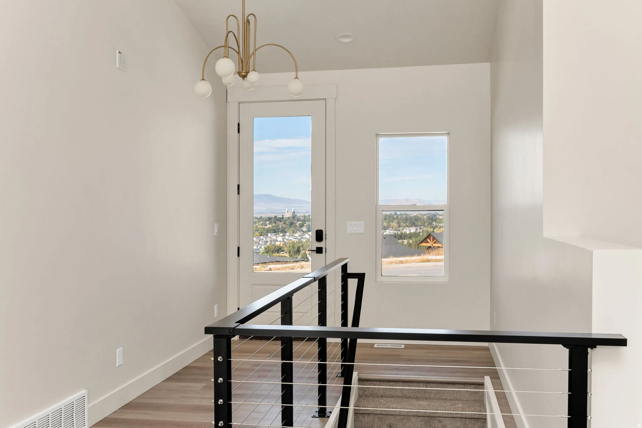 Expansive entry with a full-light door, transom window, and a contemporary chandelier