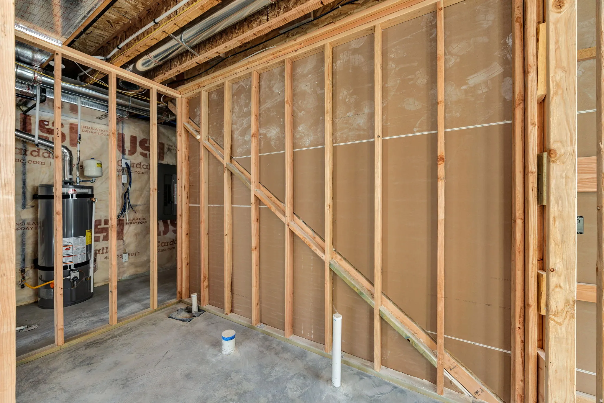 Unfinished basement space with exposed wood framing, concrete flooring, and visible plumbing rough-ins