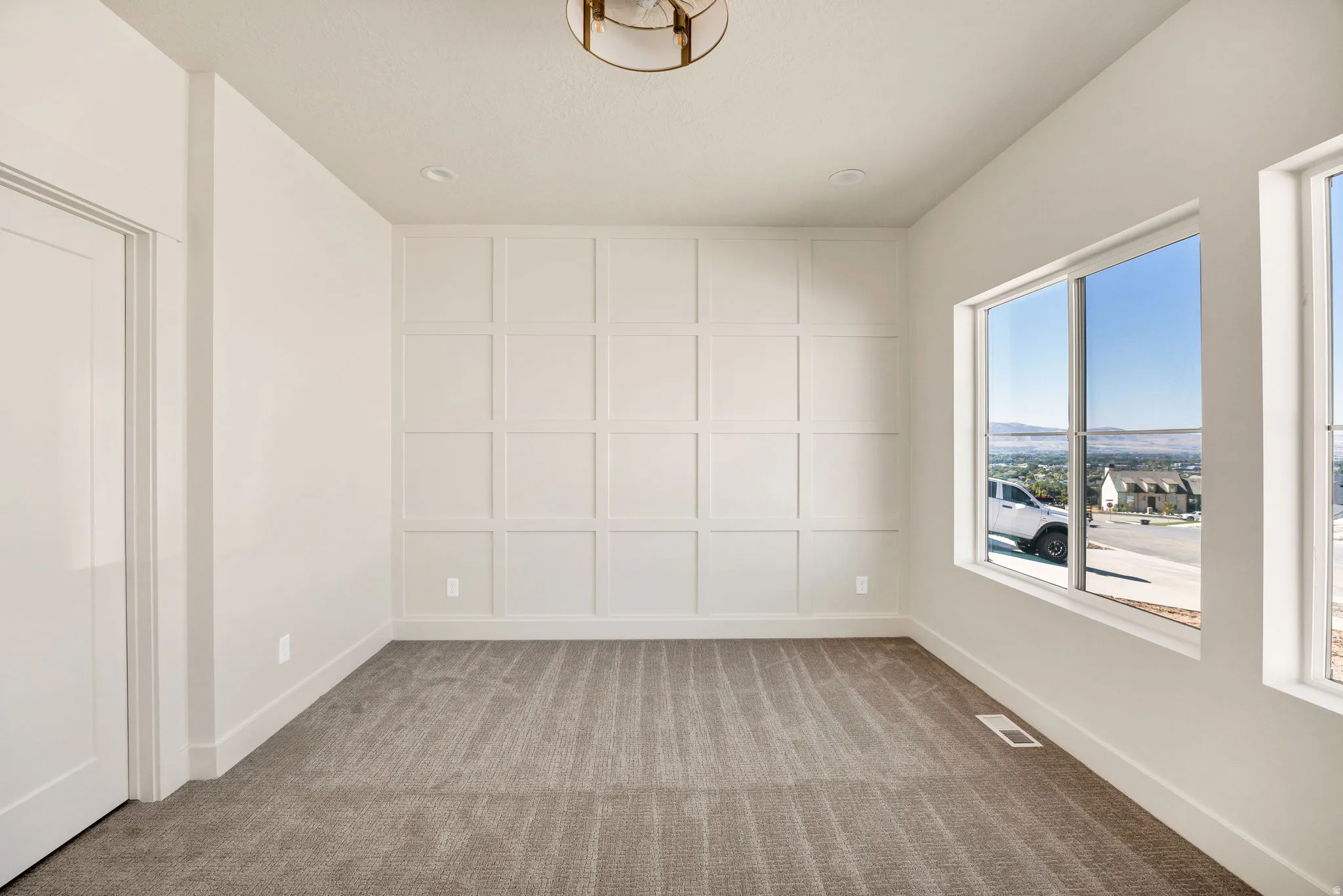 Accent wall with geometric trim, plush carpet flooring, recessed lighting, and large windows