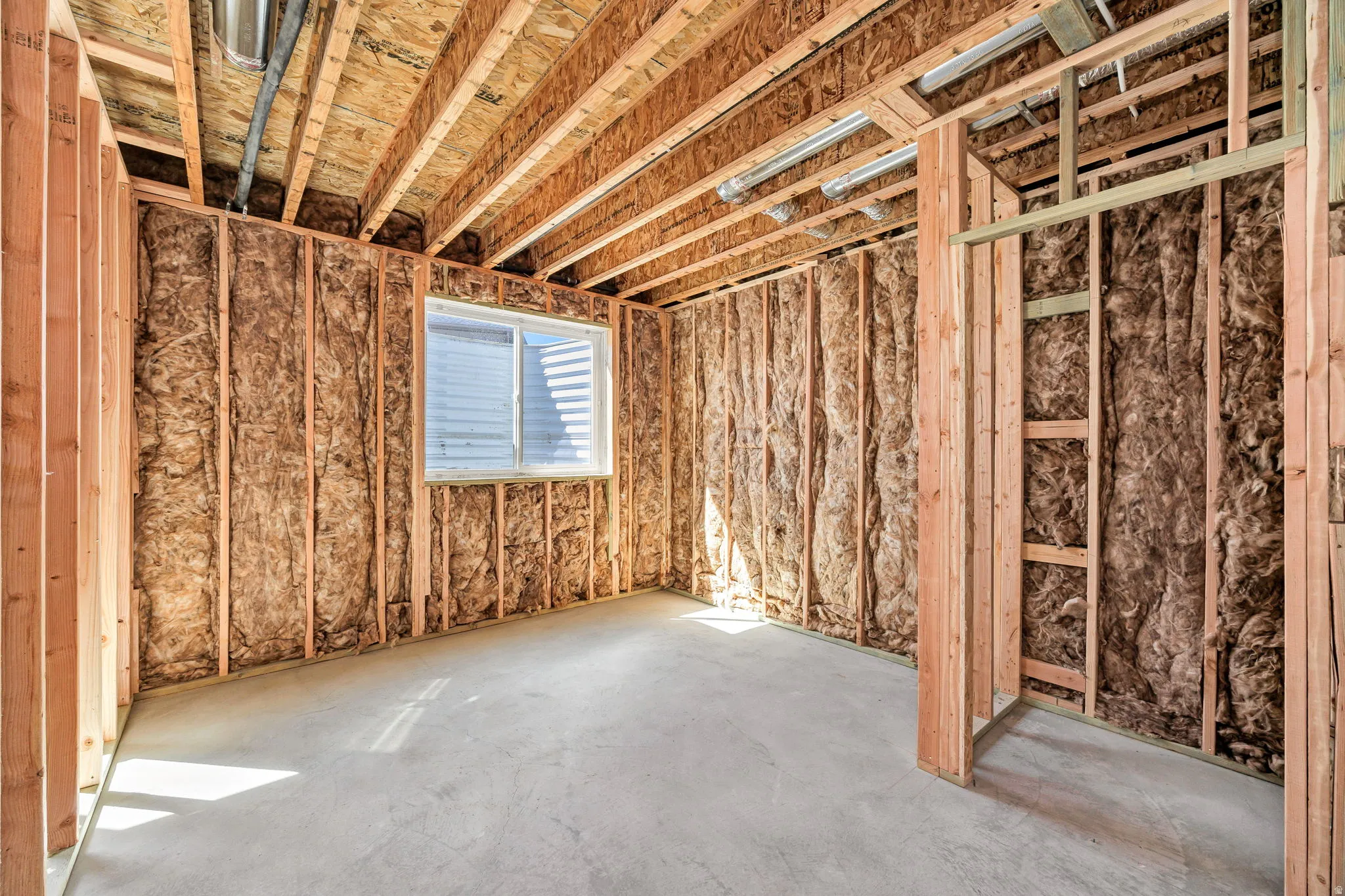 Unfinished basement with exposed wood framing, ceiling joists, and concrete flooring