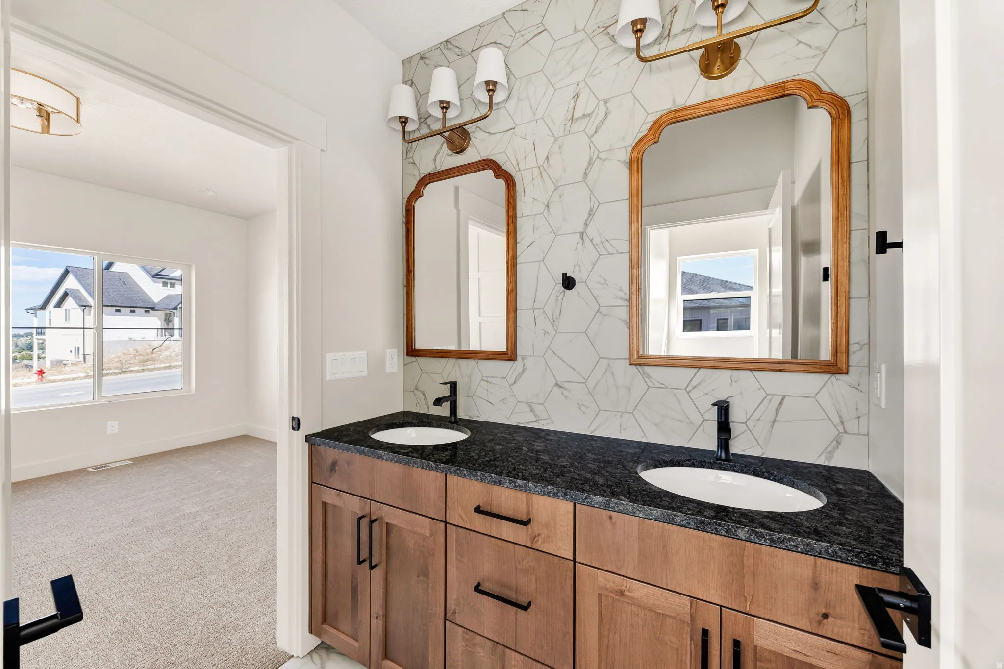 Double vanity featuring dual undermount sinks, black countertops, and wood-finish cabinetry