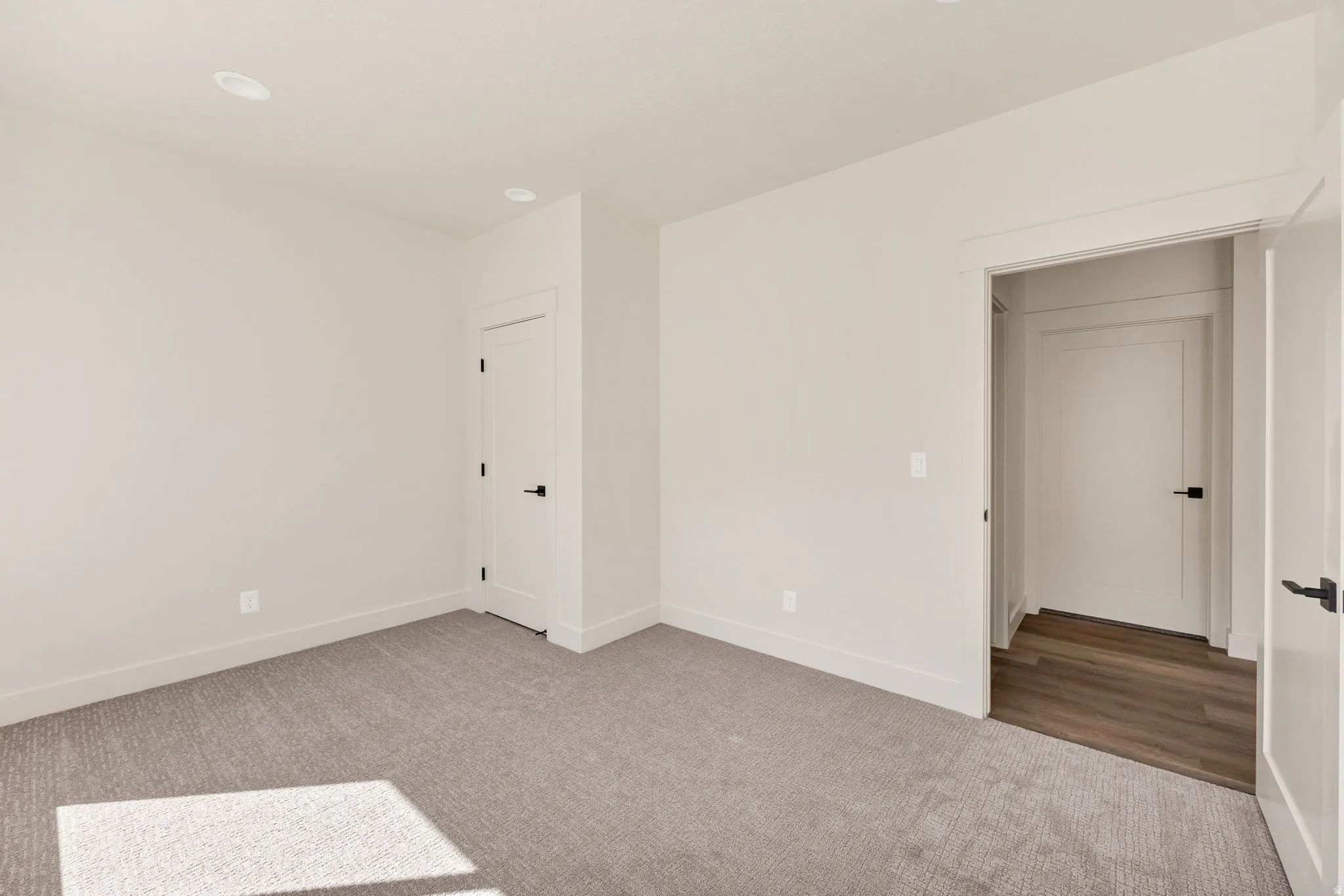 Recessed lighting, light gray carpeting, white walls, and white trim