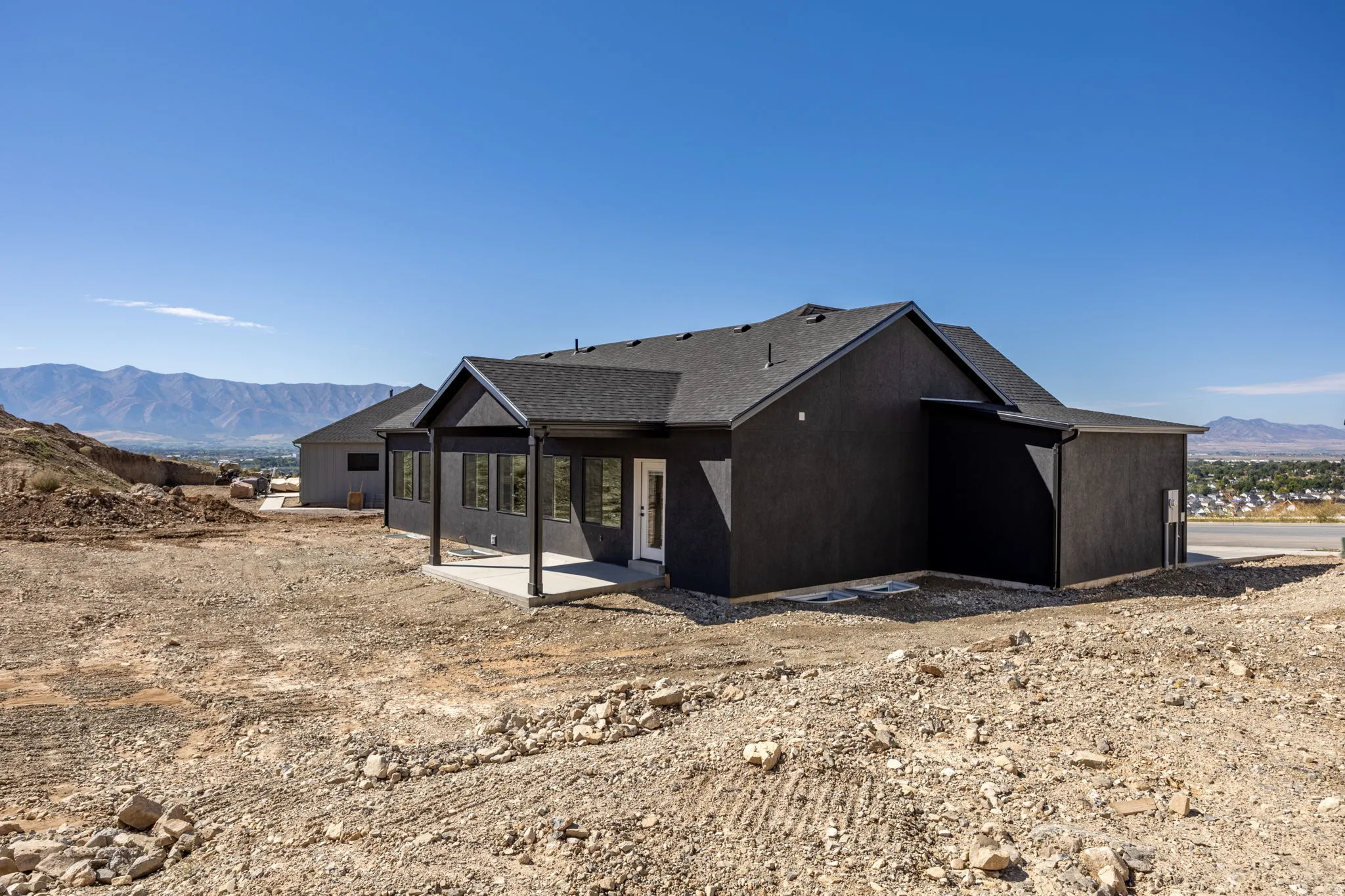 Contemporary exterior with a covered patio, multiple windows, and a dark shingle roof