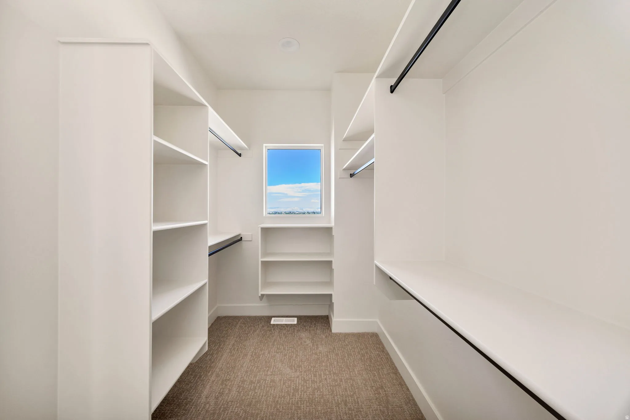 Walk-in closet featuring built-in shelving, hanging rods, and a window for natural light