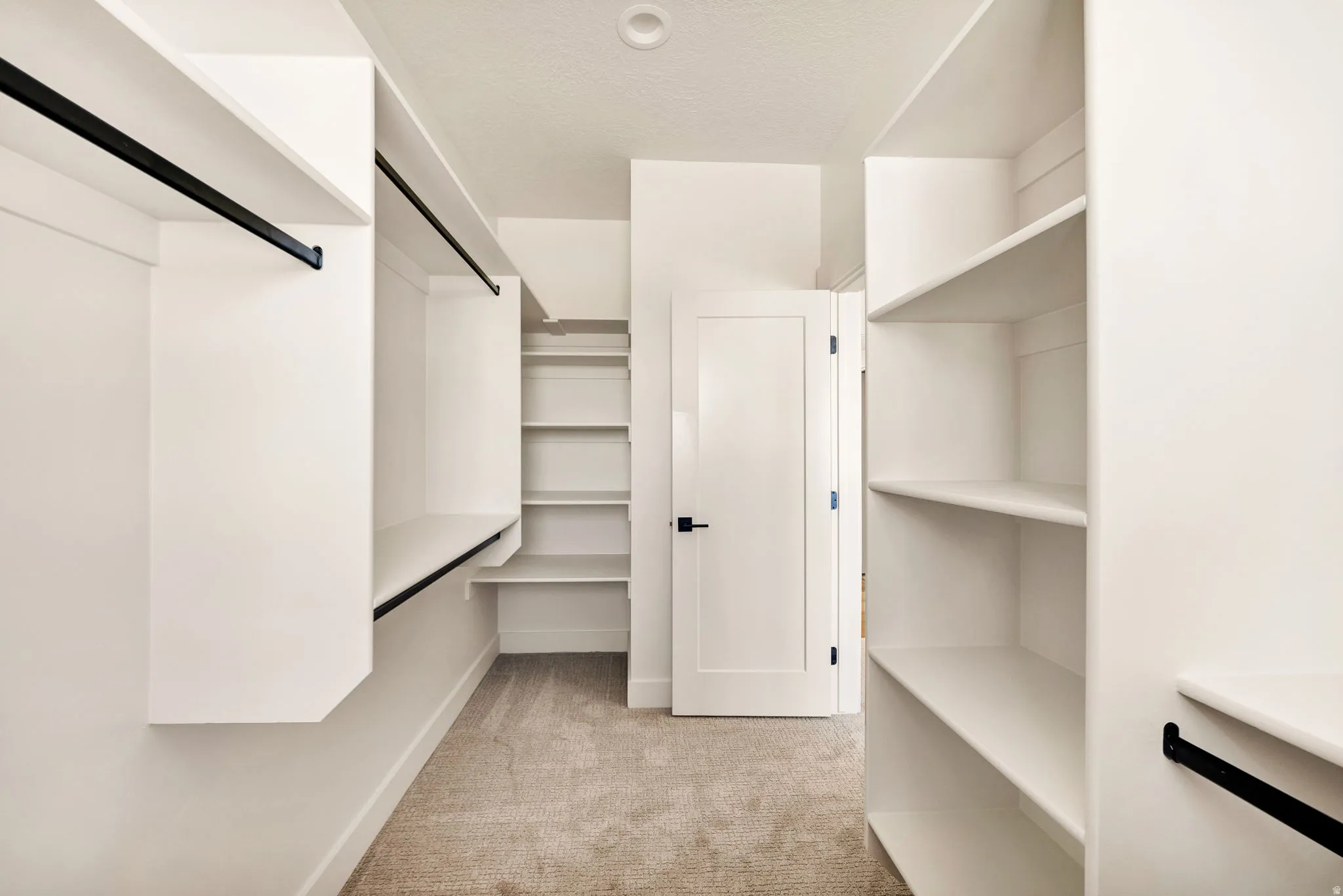 Built-in white shelving, black hanging rods, and light-colored carpeting
