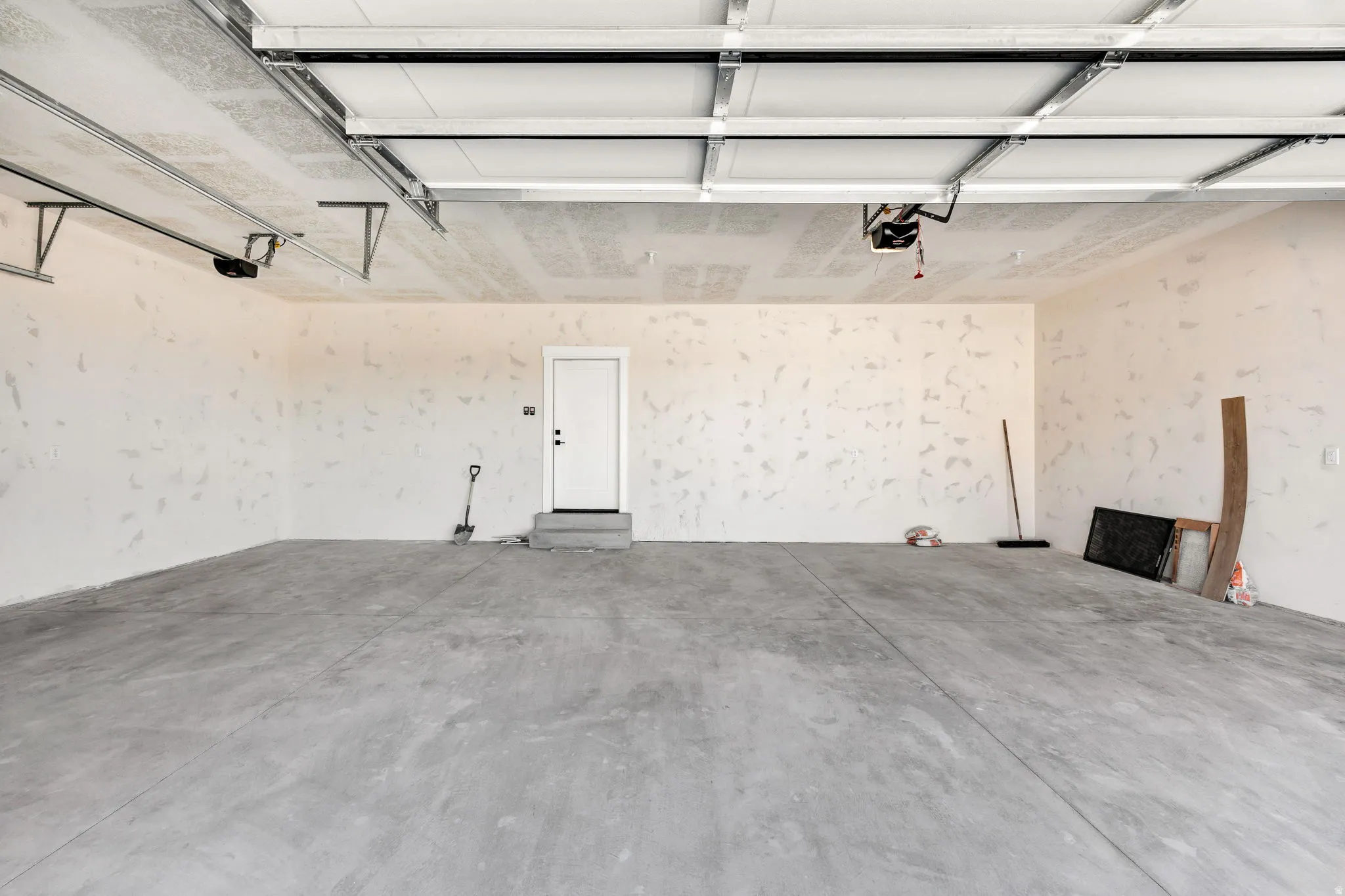 Spacious garage with concrete flooring, automatic garage door opener, and a side entry door