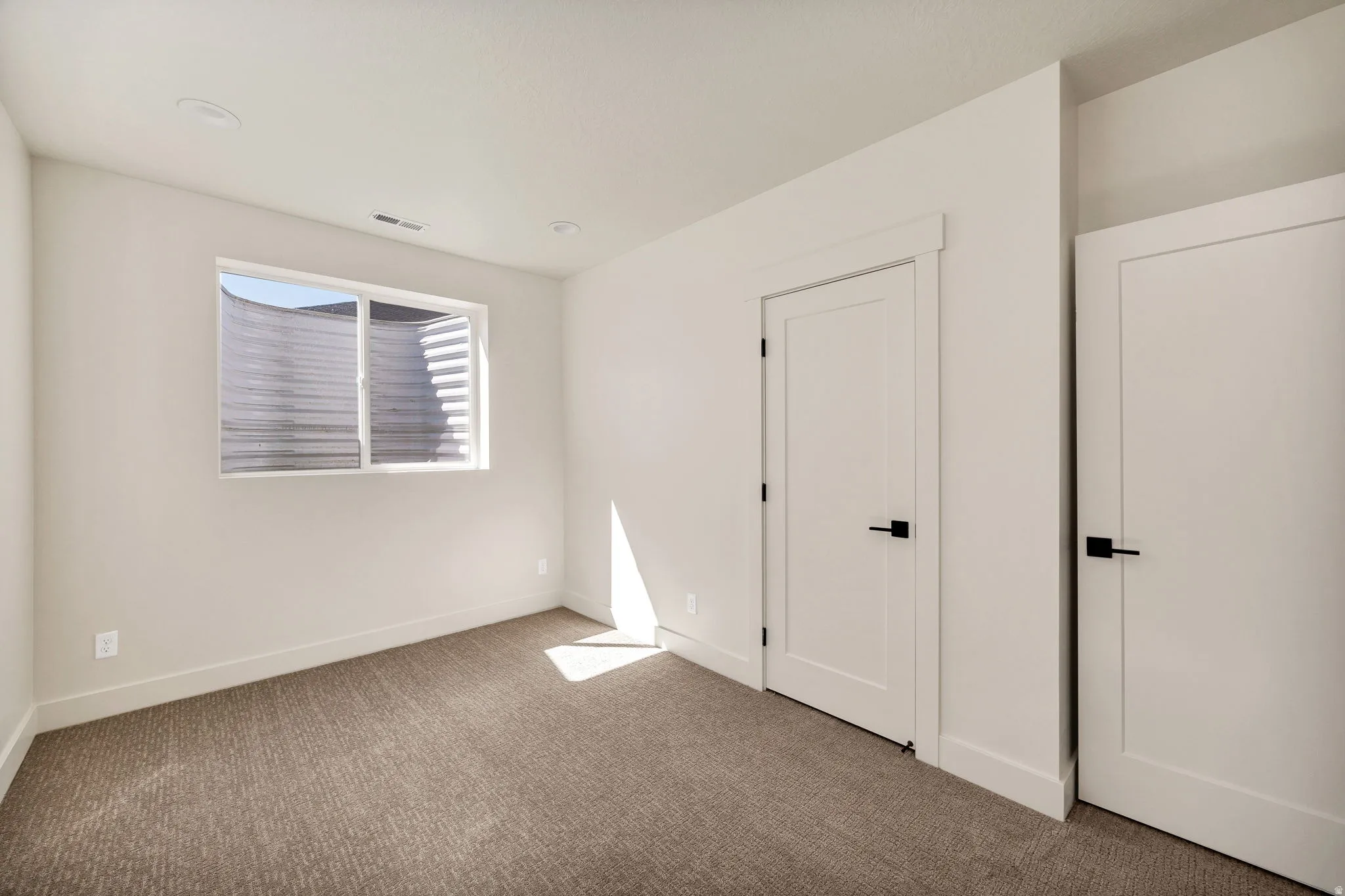 Recessed lighting, neutral wall paint, white trim, modern white doors, and dark hardware