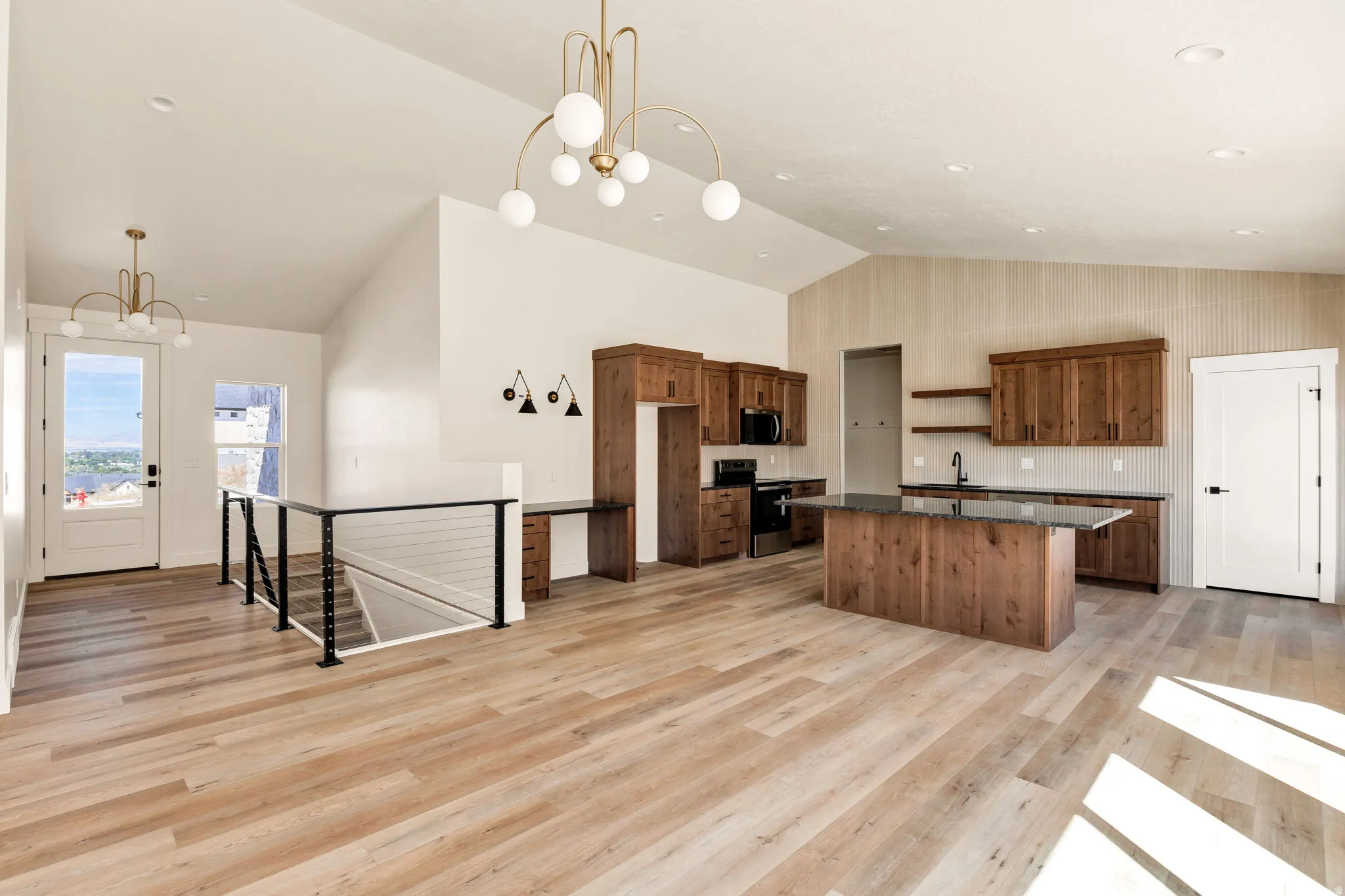 Vaulted ceilings, wood-finish flooring, contemporary lighting, wood cabinetry, and a kitchen island with stone countertop