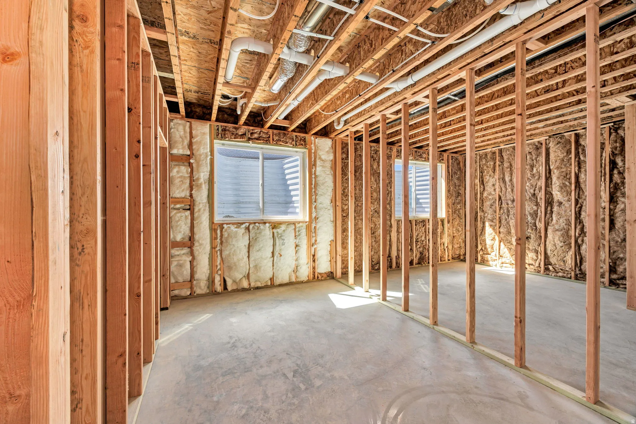 Framed interior space with exposed ceiling joists, concrete flooring, and insulated walls