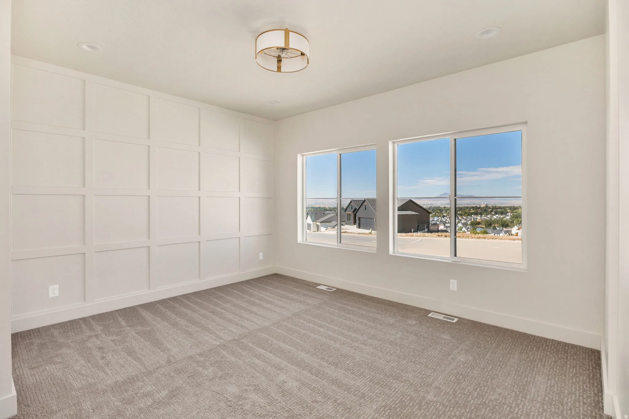 Feature wall with grid paneling, two expansive windows, recessed ceiling lighting, and a drum-style ceiling fixture
