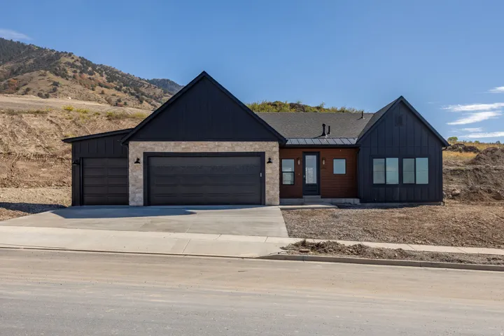 Contemporary exterior with stone accents, dark vertical siding, a front entry, and a multi-car garage