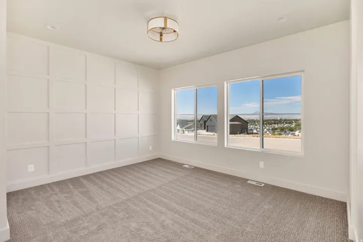 Feature wall with grid paneling, two expansive windows, recessed ceiling lighting, and a drum-style ceiling fixture