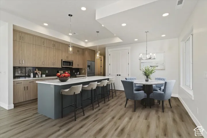 Gourmet kitchen with wood-finish cabinetry, built-in stainless steel appliances, a large island with seating, and recessed lighting