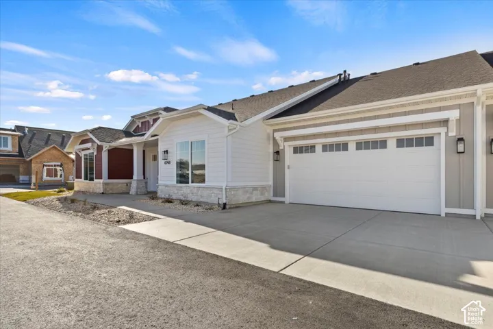 Modern single-story residence featuring a clean white exterior with architectural trim detailing, a two-car garage with paneled doors, and a concrete driveway