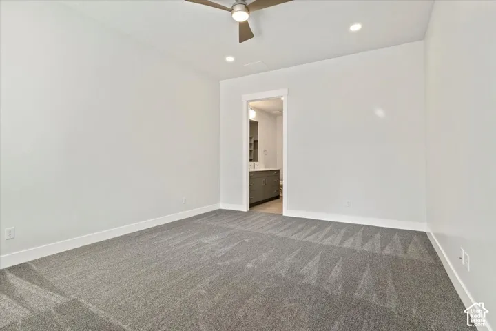 Spacious room with gray patterned carpet, white walls, recessed lighting, and a ceiling fan