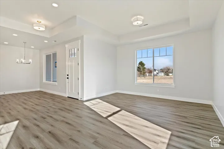 Wood-finish flooring with a multi-pane window, recessed lighting, and a white paneled entry door