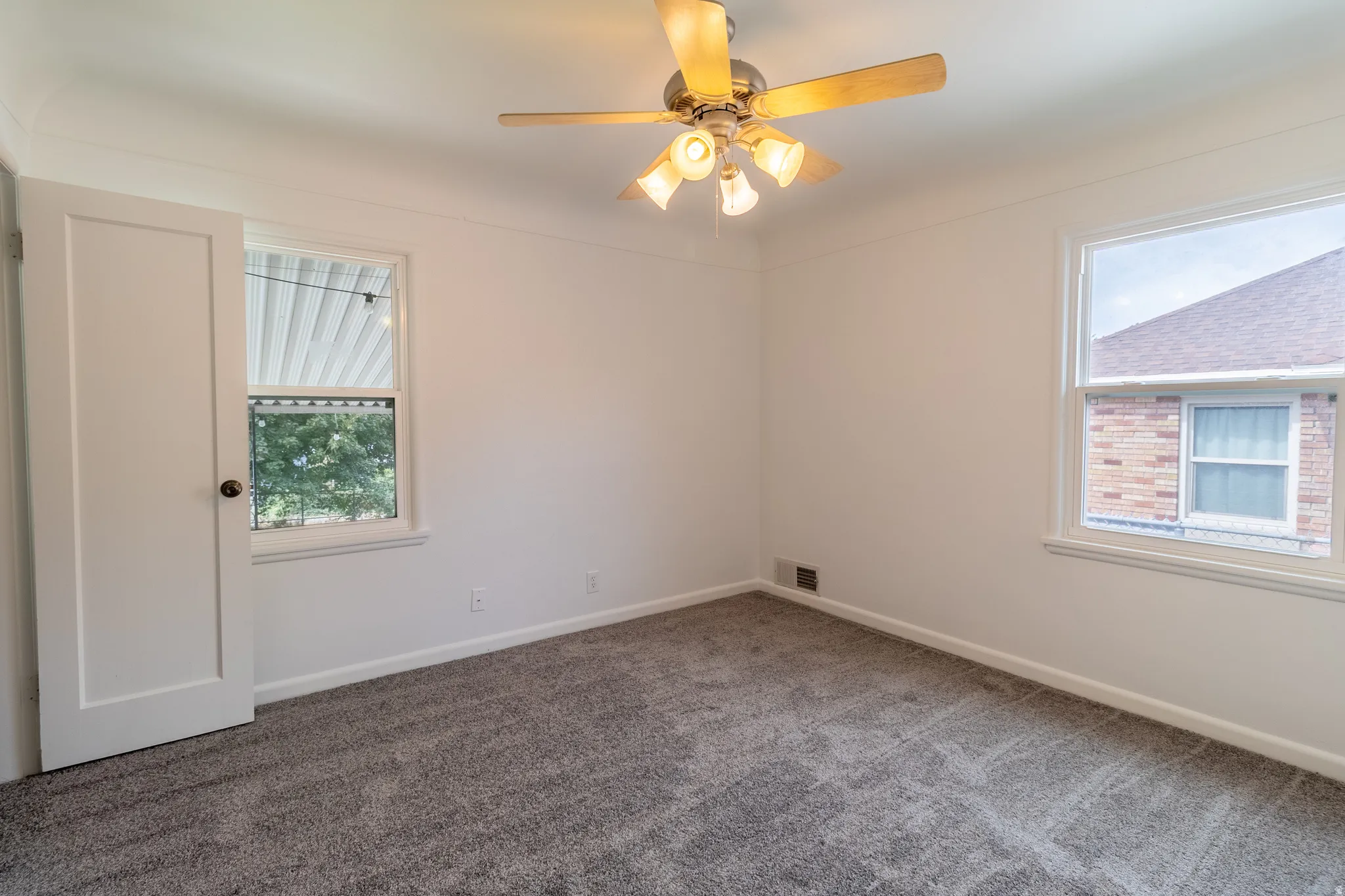 Neutral wall paint, ceiling fan with light fixture, gray patterned carpeting, and white window trim